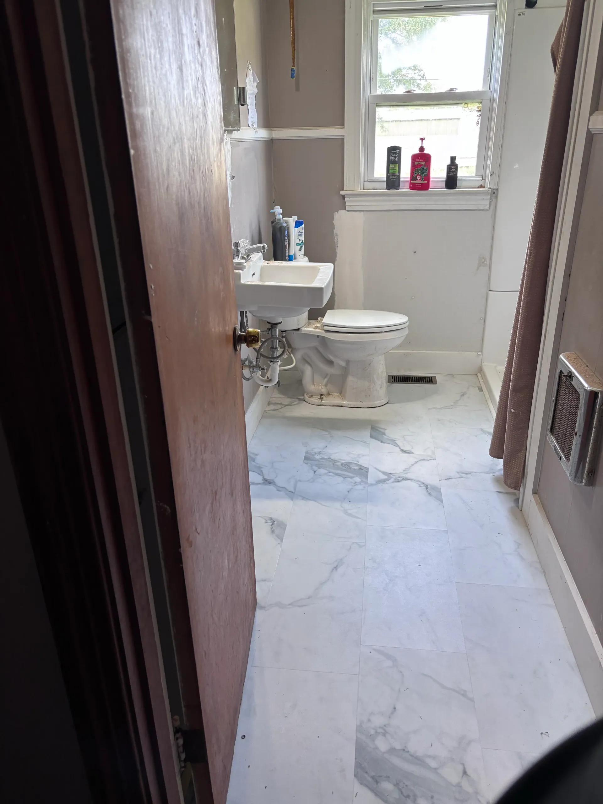 Bathroom remodel with marble-look floor tile, toilet, and sink